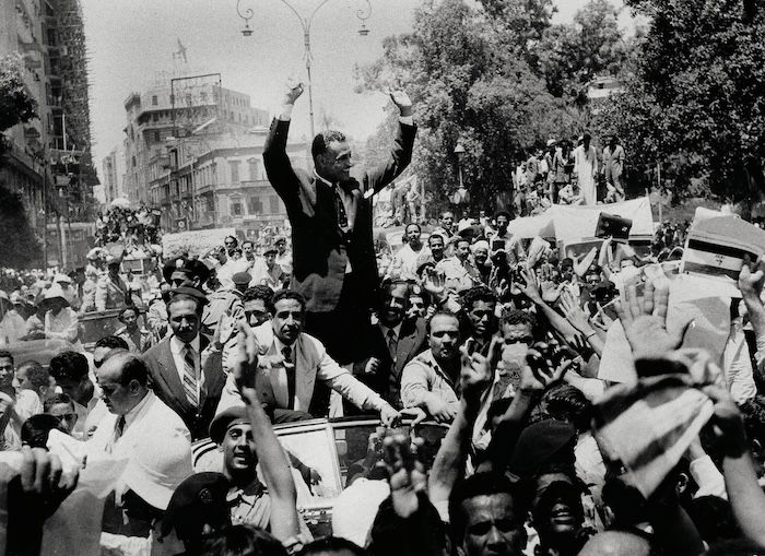 Nasser waves to crowds as he is driven through Cairo, 28 July 1956. Associated Press/Alamy Stock Photo.